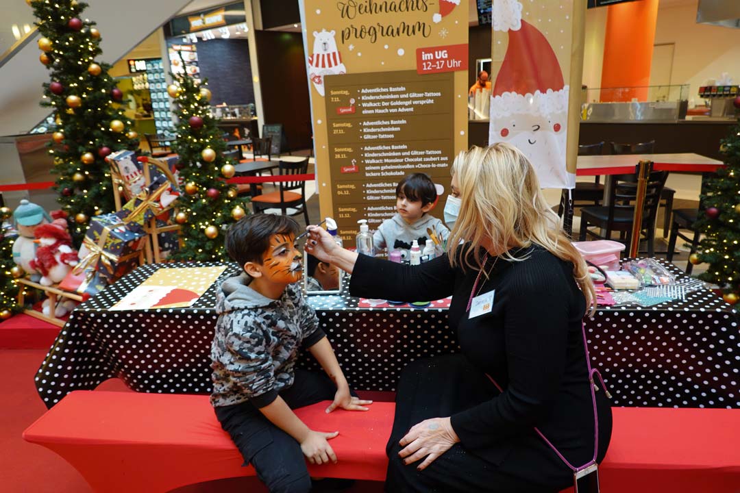 Frau malt Kindern bunte Gesichter