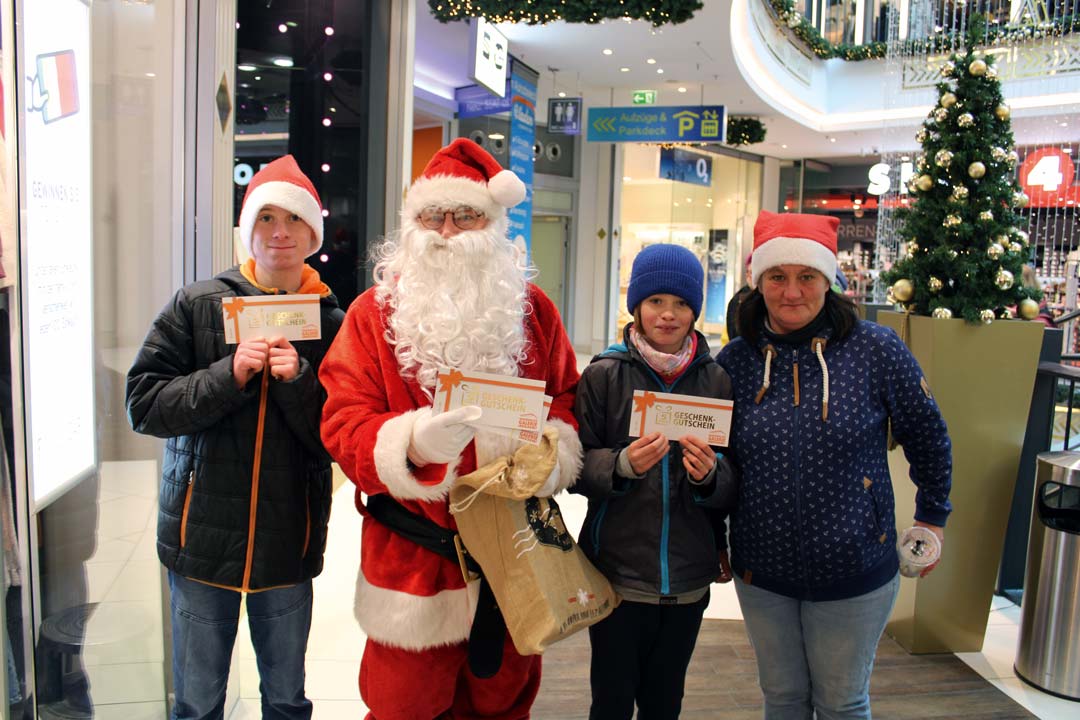 Zusehen ist der "Weihnachtsmann" mit einer beschenkten Familie in der Marienplatz-Galerie