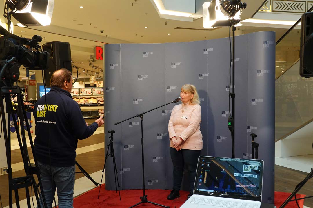 Frau vor einer aufgestellten Wand, die eine Szene nachspielt.